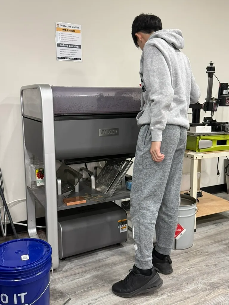 Student operating the Wazer desktop waterjet cutter
